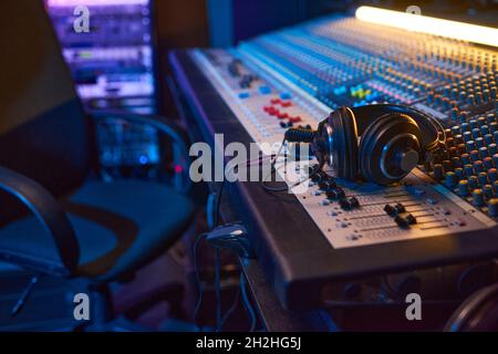 Close-up of sound mixing board with headphones on it for musical producer in studio Stock Photo