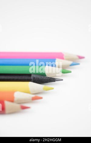Row of coloured pencils, with an odd one in black. Stock Photo