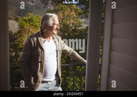 Senior caucasian man looking away at balcony on sunny day Stock Photo