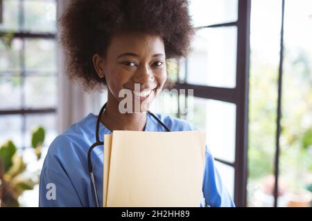 Portrait of smiling african american female doctor holding documents Stock Photo