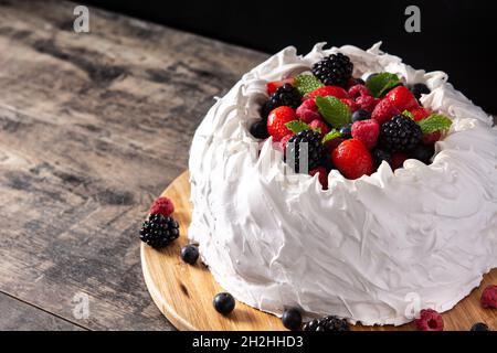 Delicious Pavlova cake with meringue topped and fresh berries on wooden table. Stock Photo