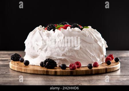 Delicious Pavlova cake with meringue topped and fresh berries on wooden table. Stock Photo