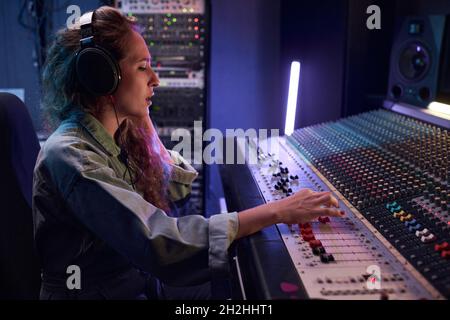 Radio DJ in headphones using music keyboard to play the music during broadcasting Stock Photo