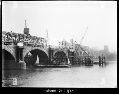 Demolition of Waterloo Bridge, Lambeth, Greater London Authority, 1936. A view across the River Thames showing the old Waterloo Bridge under demolition with a Thames sailing barge passing beneath it. The Waterloo Bridge was designed by John Rennie and opened in 1817. It was demolished in the 1930s with another bridge replacing it in the 1940s.