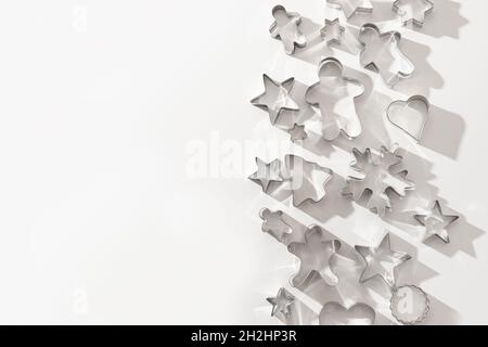 Christmas-themed cookie cutters for gingerbread on white background. Xmas creative concept and greeting card. Top view, flat lay. Stock Photo