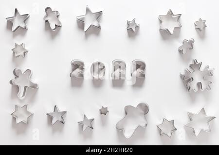 Christmas-themed cookie cutters for gingerbread as frame on white background. New Year creative concept and greeting card. Top view, flat lay. Happy N Stock Photo