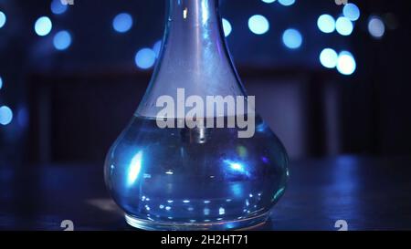 Glass bowl of hookah on the table, traditional East relaxation. Close up of transparent glass flask filled with water and smoke at the night club or b Stock Photo