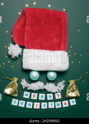 Red santa hat with blue balls, white cotton mustache and golden pouches on an emerald background Stock Photo
