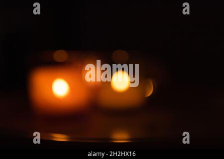 Blurry photo of burning candles on a dark background, multicolored. Abstract bokeh, background. Stock Photo