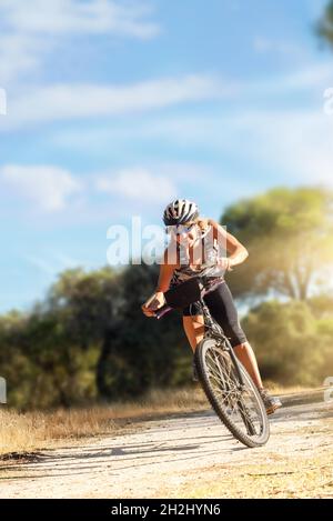 Woman bicyclist riding her bicycle in the countryside at sunset. Athlete on mountain bike at full speed Stock Photo