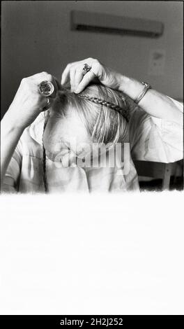 Old female mental patient braiding her hair at mental hospital Beckomberga sjukhus in Stockholm, Sweden. Stock Photo