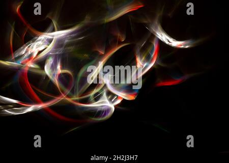Colored lights forming abstract shapes and patterns on a black background. Free space to write. Long exposure light-painting photography. Stock Photo
