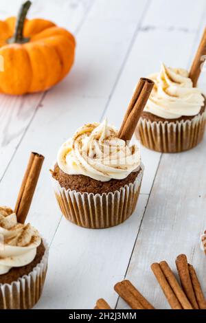 Three pumpkin spice cupcakes in a row on a wooden table. Stock Photo