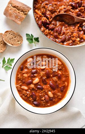 Cowboy beans with ground beef, jalapeno pepper and bacon in bowl over light stone background. Top view, flat lay, close up Stock Photo
