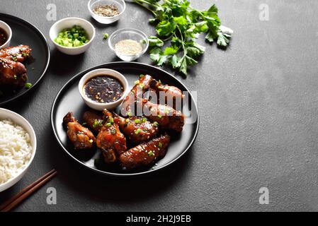 Sticky honey-soy chicken wings on plate over dark stone background with free text space. Stock Photo