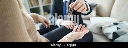 Man in business suit giving keys to apartment to disabled woman in wheelchair closeup Stock Photo