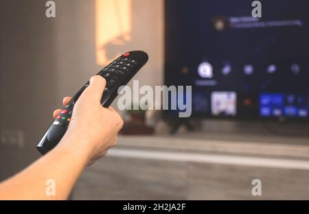 Modern living room with big Smert TV. Hand with remote control on television background photo Stock Photo