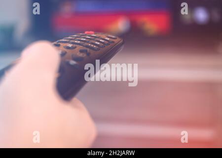 Smart TV remote control in hand. Controller for TV switches channels, streaming services etc. smart living room concept Stock Photo