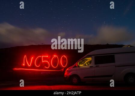 A long exposure light painting of a campervan on the NC 500 route in scotland with the words NC500 written in light under a starry night sky Stock Photo