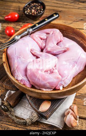 Rabbit legs uncooked in a wooden plate. Wooden background. Top view Stock Photo