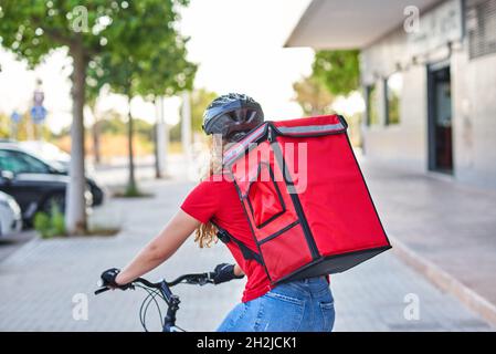 Unrecognizable food delivery woman riding bicycle in city Stock Photo