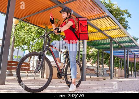 A cyclist delivery woman checks the order address on her smartphone Stock Photo