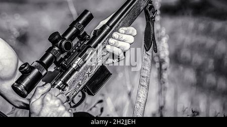 Hunter man. Hunting period. Male with a gun, rifle. Man is charging a hunting rifle. Process of hunting during hunting season. Male hunter in ready to Stock Photo