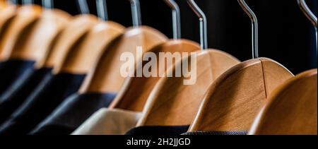 Mens shirts, suit hanging on rack. Mens suits in different colors hanging on hanger in a retail clothes store, close-up Stock Photo