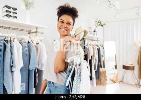Young fashion store owner carrying clothes on hangers for arranging Stock Photo