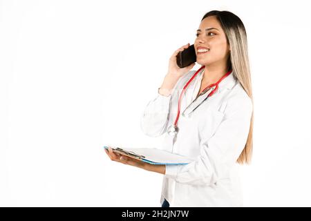 A Young female doctor talking on the cell phone and communicating good news with a medical history in hand. Concept of professional woman, personal he Stock Photo