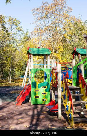 colorful wooden rides, slides and houses on children's playground in public city park on sunny autumn day Stock Photo