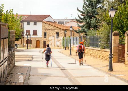 Two pilgrims walking the Camino de Santiago the way of St James through the Spanish village of Obanos after walking from Pamplona Spain Stock Photo