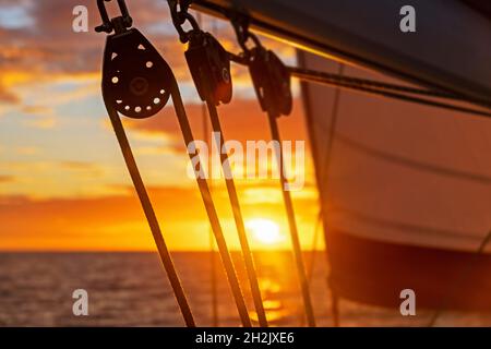 Close up of sailing boat blocks / sailboat pulleys silhouetted against orange sunset sky over the Caribbean Sea Stock Photo