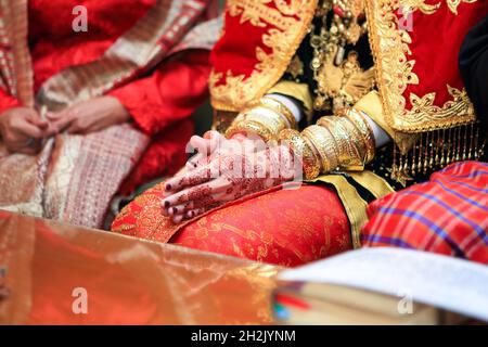 Close up hands and nails of Asian Muslim bride with henna paint tattoo and jewelry in a traditional minangkabau culture wedding ceremony