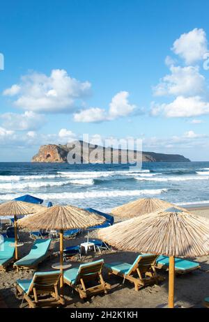 Crete island Greece Charming small resort of Agia Marina,  Chania Sun loungers and parasols on the beach View to Theodori island Portrait aspect with Stock Photo