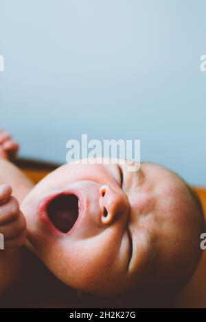Closeup of a baby boy yawning on a changing table Stock Photo