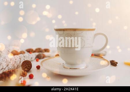 white and golden tea cup on a plate with cones, acorns,  mountain ash Stock Photo