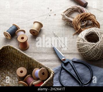 Sewing threads and instruments. Scissors and spools of thread with a needles on a canvas Stock Photo