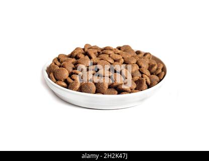 Dry pet food in a white ceramic bowl isolated on white background. Stock Photo
