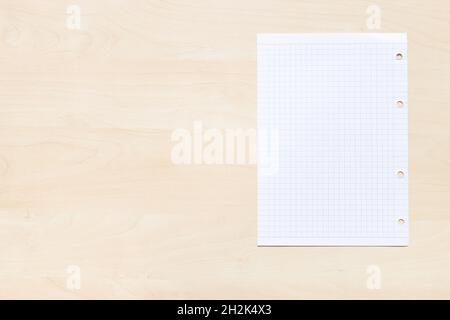 top view of blank sheet of squared paper on light brown wooden board with copyspace Stock Photo