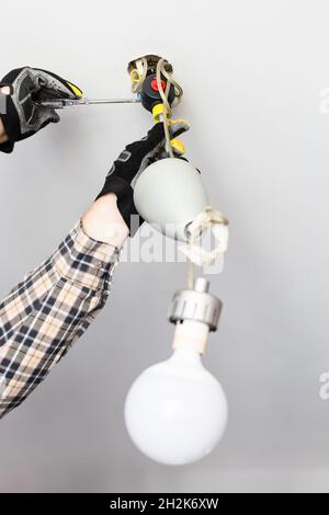 electrician removing fault ceiling lamp at home Stock Photo