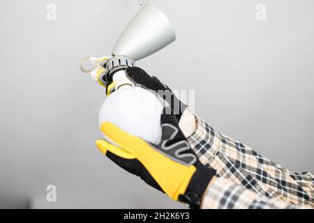 electrician removing bulb from fault ceiling light at home Stock Photo