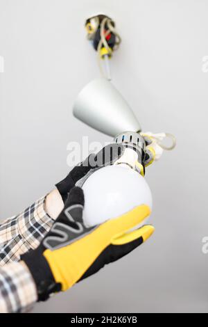 electrician remove bulb from defective ceiling light at home Stock Photo
