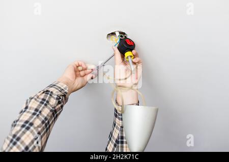 man repairing defected ceiling lamp at home Stock Photo