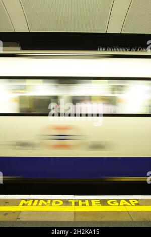 LONDON, UNITED KINGDOM - Sep 15, 2021: A vertical shot of a train caught in motion with a 'Mind The Gap' writing at a tube station in London, the UK Stock Photo