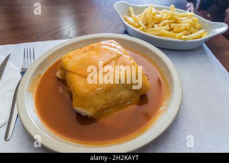 Sandwich called Francesinha served with french fries, typical dish in Porto, Portugal Stock Photo