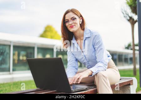 Young confident redhead woman programmer online communication in park Stock Photo