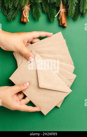 woman hands hold stack of craft beige envelopes, concept of sending Christmas greetings Stock Photo