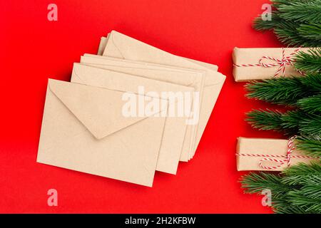 Christmas card from stack of craft envelopes with frame of Christmas decorations on isolated red background Stock Photo