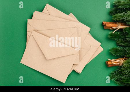 Christmas card from stack of craft envelopes with frame of Christmas decorations on isolated green background Stock Photo